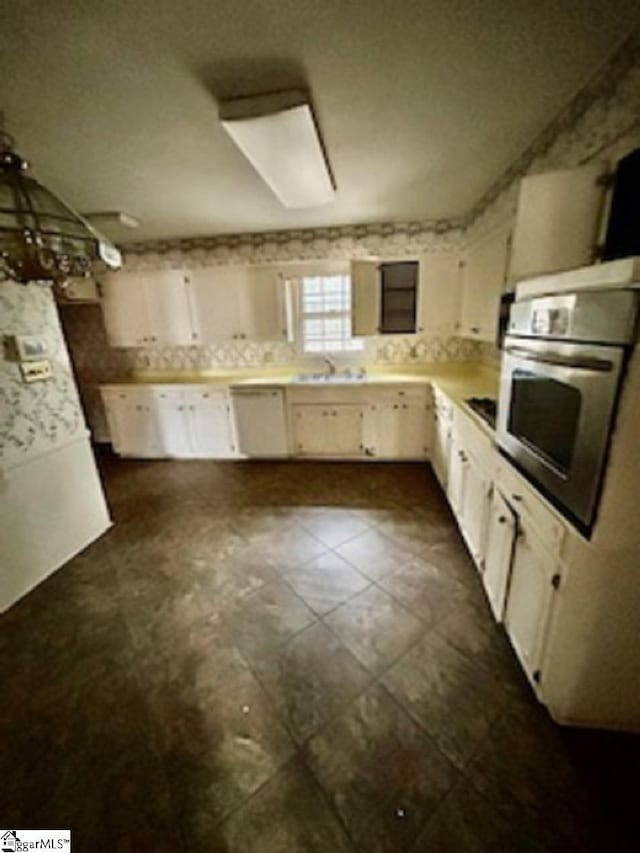 kitchen with sink, white cabinetry, dishwashing machine, oven, and black stovetop