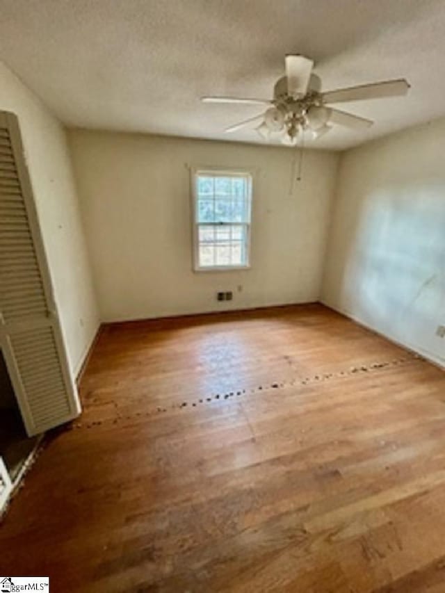 spare room featuring ceiling fan, hardwood / wood-style floors, and a textured ceiling