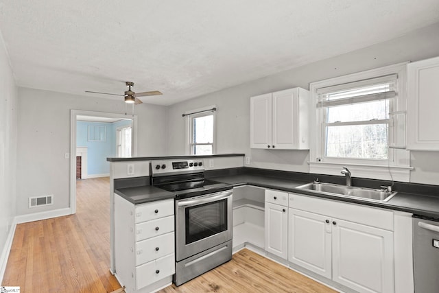 kitchen with light wood-type flooring, appliances with stainless steel finishes, sink, and white cabinets