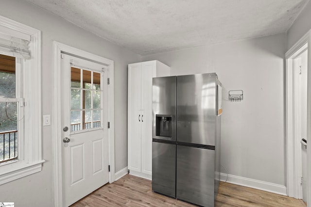 kitchen with stainless steel fridge with ice dispenser, light hardwood / wood-style floors, and white cabinets