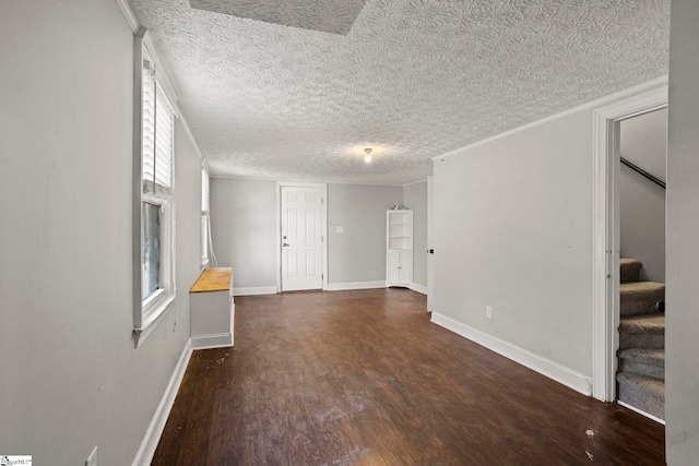 unfurnished living room with dark hardwood / wood-style flooring, ornamental molding, and a textured ceiling