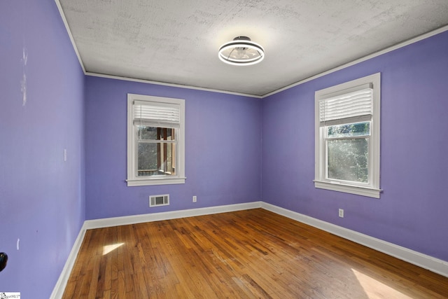 unfurnished room with hardwood / wood-style floors, ornamental molding, and a textured ceiling