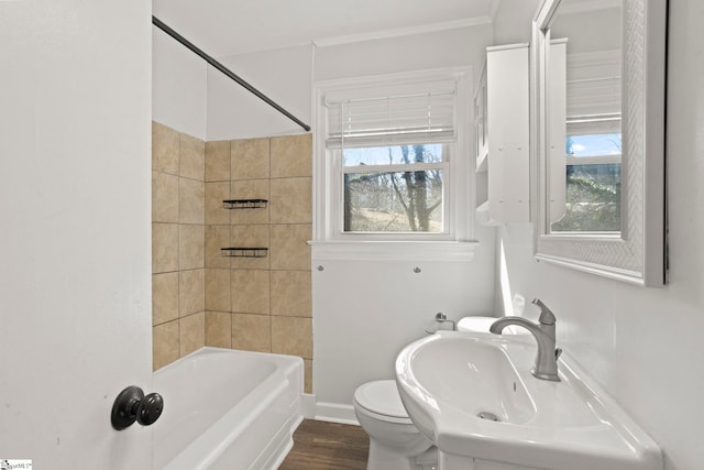 full bathroom featuring sink, tiled shower / bath combo, toilet, and a healthy amount of sunlight