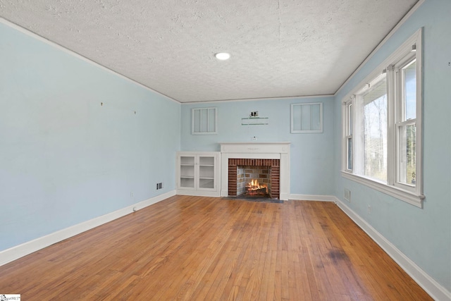 unfurnished living room featuring hardwood / wood-style flooring, a fireplace, and a textured ceiling