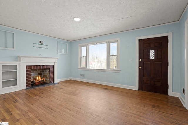 unfurnished living room with hardwood / wood-style flooring, a fireplace, and a textured ceiling