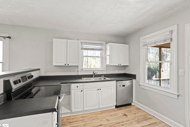 kitchen featuring sink, white cabinetry, stainless steel appliances, light hardwood / wood-style floors, and a textured ceiling