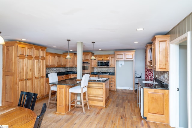 kitchen with appliances with stainless steel finishes, pendant lighting, sink, a breakfast bar area, and a center island with sink