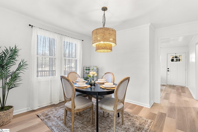 dining area featuring crown molding, a chandelier, and light wood-type flooring