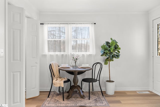 dining room featuring crown molding, light hardwood / wood-style flooring, and a wealth of natural light