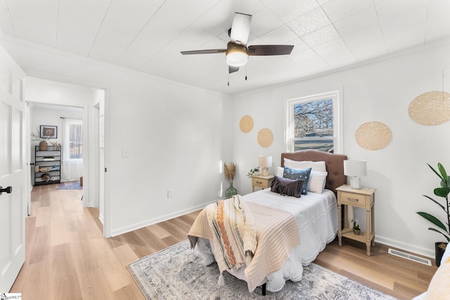 bedroom featuring multiple windows, light hardwood / wood-style flooring, and ornamental molding