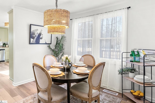 dining room featuring a notable chandelier, crown molding, and light hardwood / wood-style flooring