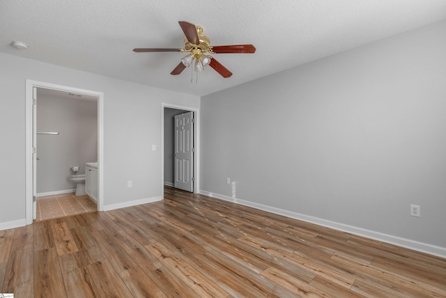 unfurnished bedroom with ensuite bathroom, ceiling fan, a textured ceiling, and light hardwood / wood-style floors