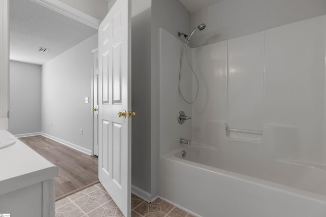 bathroom with vanity, tub / shower combination, wood-type flooring, and a textured ceiling