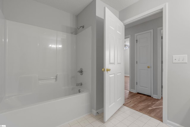 bathroom featuring tile patterned flooring, washtub / shower combination, and a textured ceiling