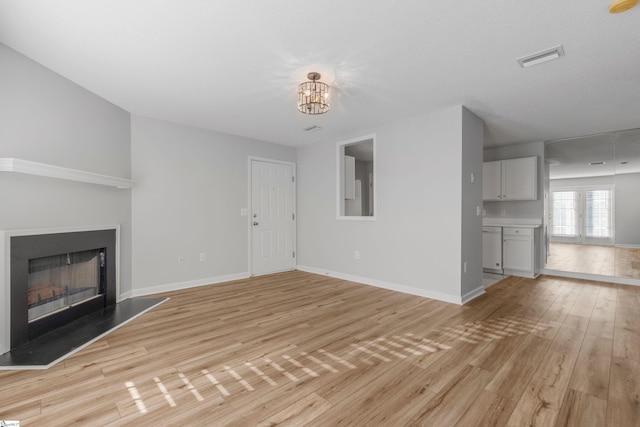 unfurnished living room featuring light hardwood / wood-style floors and a chandelier