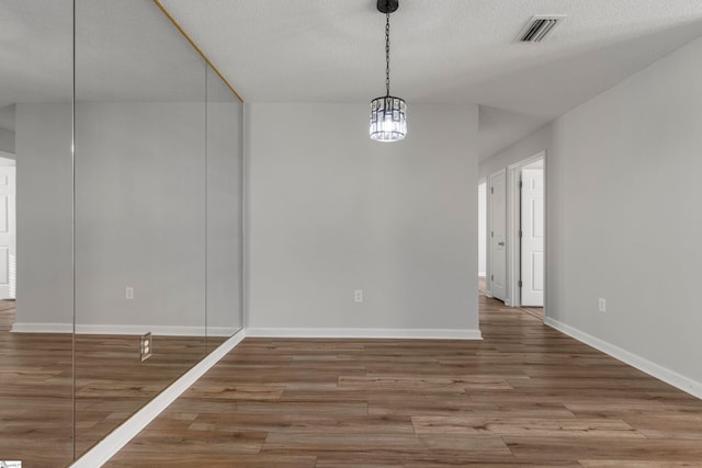 unfurnished dining area with hardwood / wood-style floors and a textured ceiling