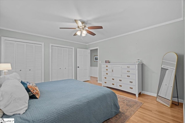 bedroom featuring multiple closets, ceiling fan, crown molding, and light wood-type flooring