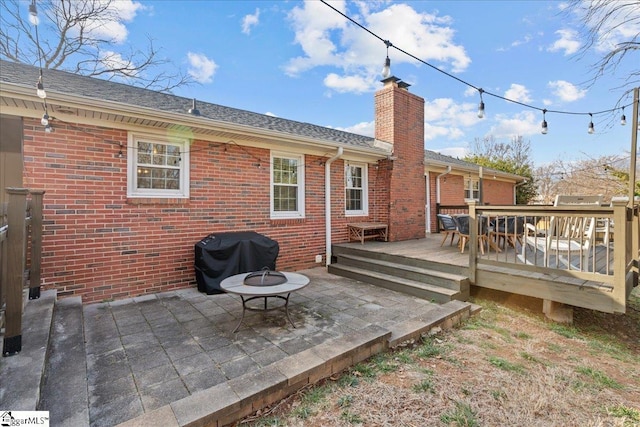 back of property featuring a deck, a patio area, and a fire pit