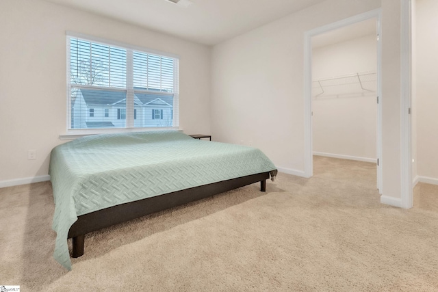 bedroom featuring light colored carpet, a spacious closet, and a closet