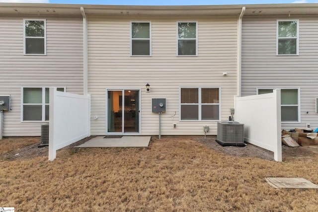 rear view of property featuring a lawn and central air condition unit