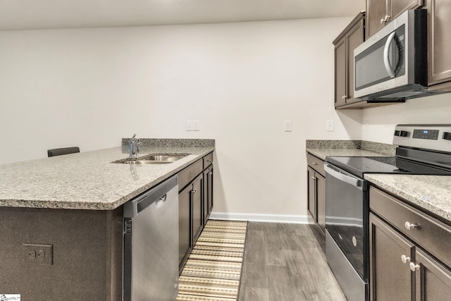 kitchen featuring stainless steel appliances, wood-type flooring, sink, and dark brown cabinets