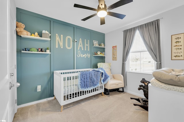 carpeted bedroom with a nursery area and ceiling fan