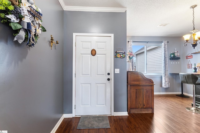 entryway featuring crown molding, a textured ceiling, dark wood-type flooring, and a chandelier