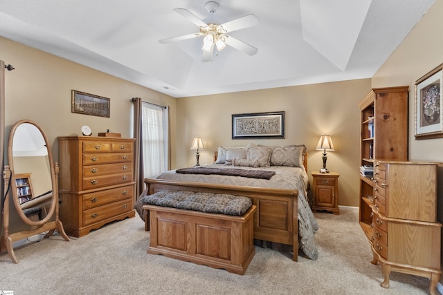 bedroom with a raised ceiling, light carpet, and ceiling fan