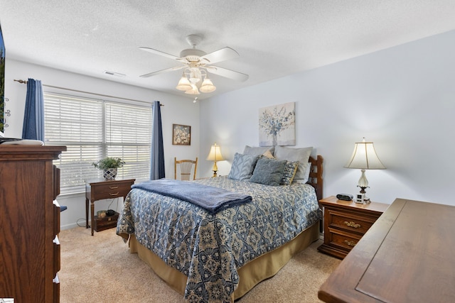 carpeted bedroom featuring ceiling fan and a textured ceiling