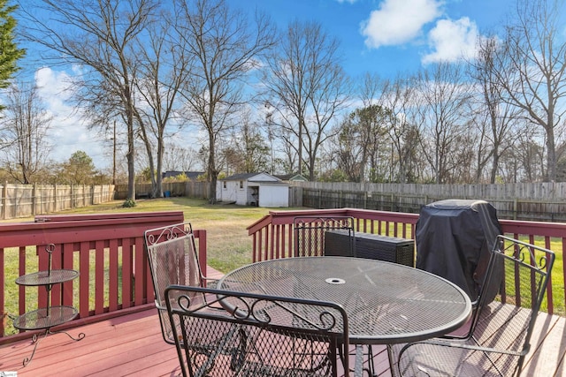 wooden terrace featuring a storage shed, a lawn, and grilling area