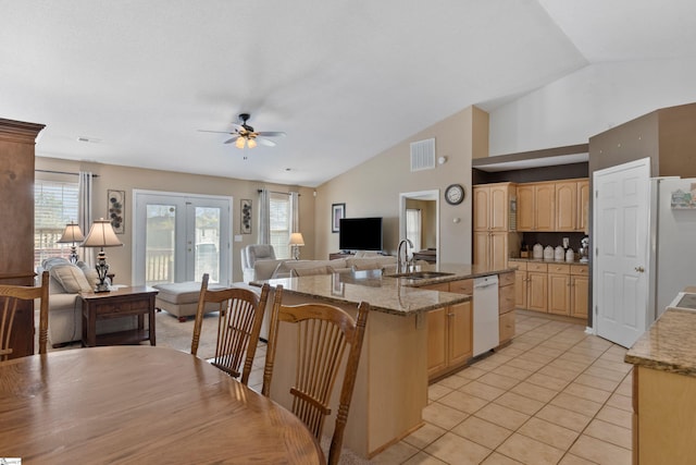 kitchen with sink, dishwasher, a kitchen island with sink, light tile patterned flooring, and light brown cabinetry