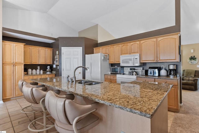 kitchen with white appliances, sink, a breakfast bar, and an island with sink