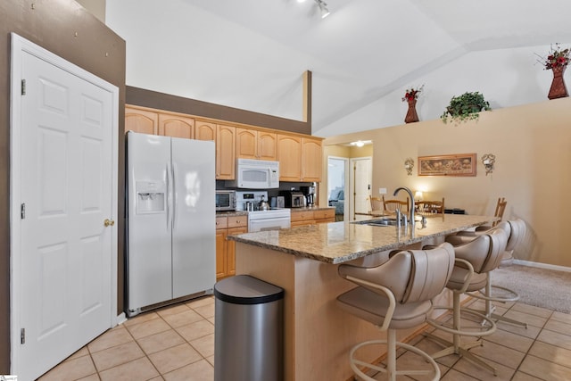 kitchen featuring light brown cabinetry, sink, light tile patterned floors, white appliances, and light stone countertops