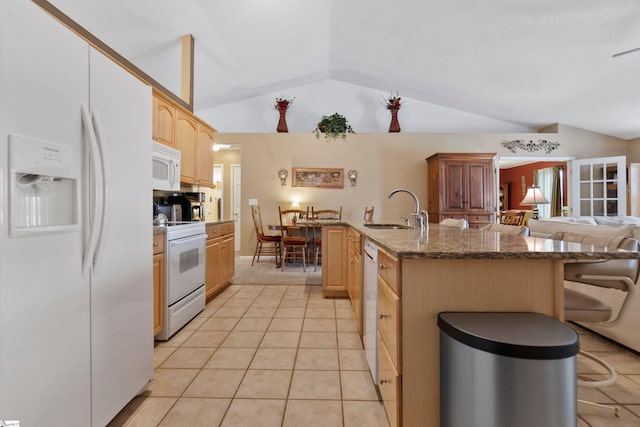 kitchen featuring sink, white appliances, vaulted ceiling, and a kitchen breakfast bar