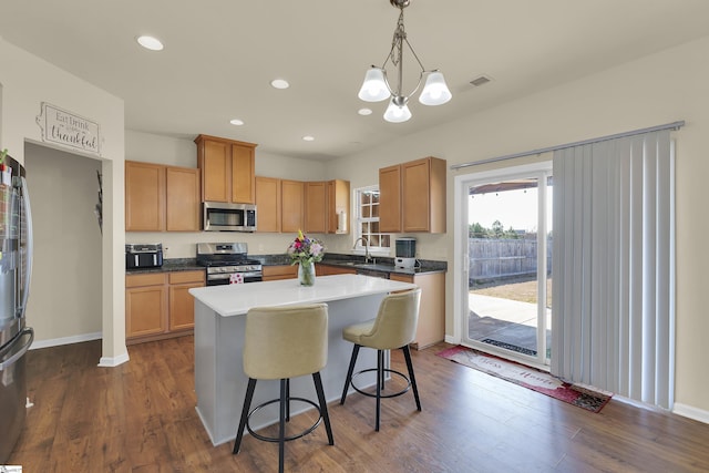 kitchen featuring stainless steel appliances, dark hardwood / wood-style floors, hanging light fixtures, and a kitchen island