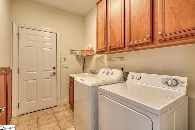 clothes washing area with cabinets, washing machine and clothes dryer, sink, and light tile patterned floors