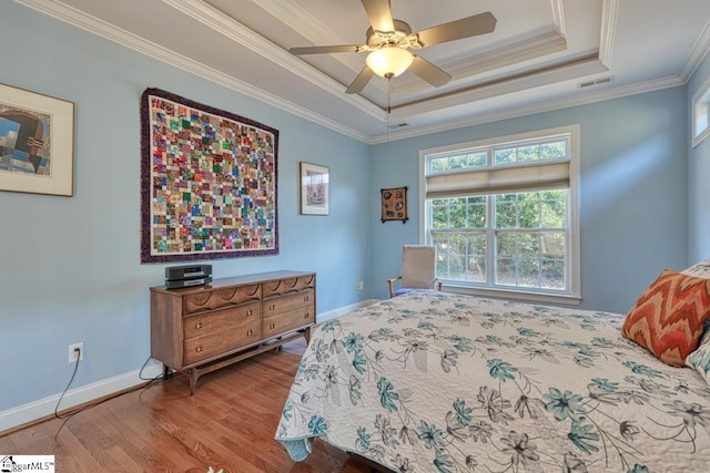 bedroom with crown molding, ceiling fan, a raised ceiling, and hardwood / wood-style floors