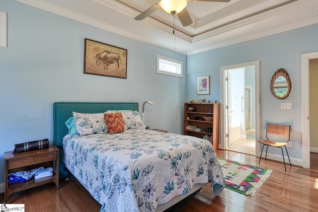 bedroom featuring crown molding, hardwood / wood-style floors, a tray ceiling, and ceiling fan