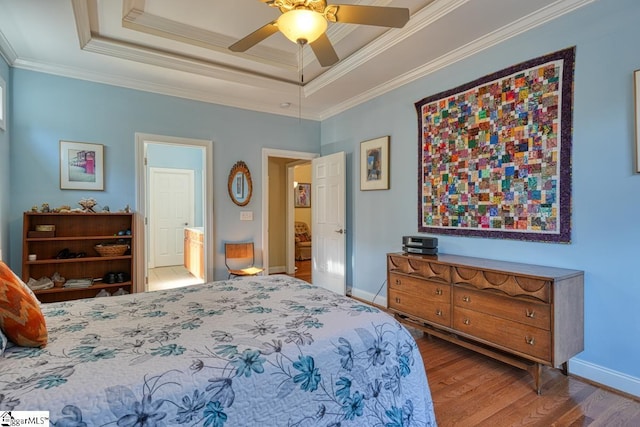 bedroom with crown molding, ceiling fan, wood-type flooring, and a tray ceiling