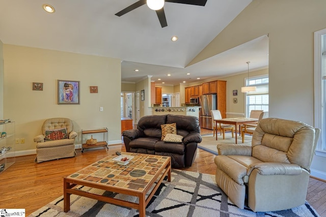 living room with crown molding, high vaulted ceiling, and light hardwood / wood-style flooring