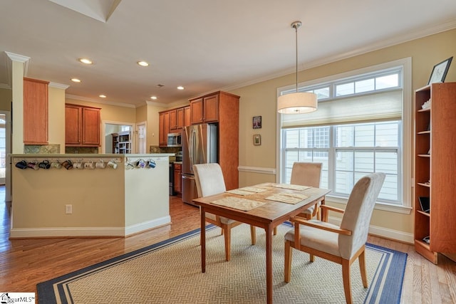 dining space featuring crown molding and light wood-type flooring