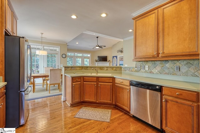 kitchen featuring sink, crown molding, hanging light fixtures, appliances with stainless steel finishes, and kitchen peninsula