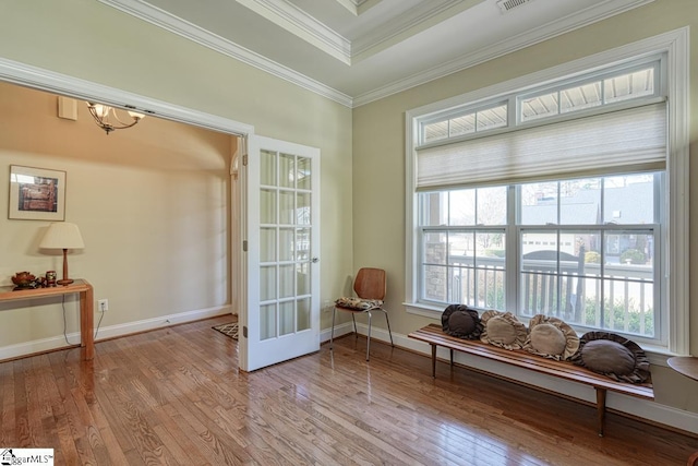 sitting room featuring a raised ceiling, crown molding, light wood-type flooring, and french doors