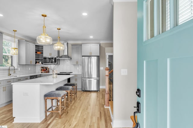 kitchen featuring gray cabinetry, stainless steel appliances, a center island, and wall chimney exhaust hood