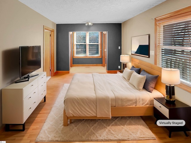 bedroom with a textured ceiling and light wood-type flooring