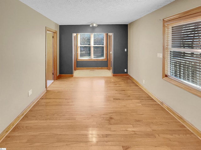 empty room featuring a textured ceiling and light hardwood / wood-style floors