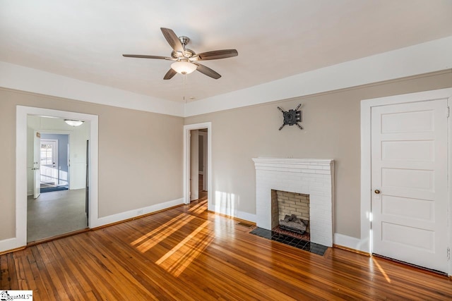 unfurnished living room featuring hardwood / wood-style flooring, a brick fireplace, and ceiling fan