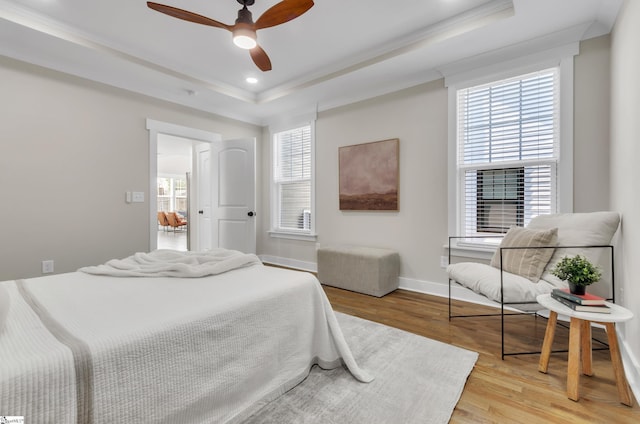 bedroom featuring crown molding, ceiling fan, a tray ceiling, and light hardwood / wood-style floors