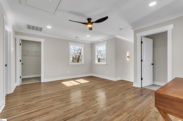 unfurnished bedroom featuring ornamental molding, a spacious closet, ceiling fan, and light hardwood / wood-style floors