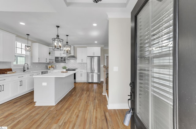 kitchen featuring appliances with stainless steel finishes, decorative light fixtures, a center island, and white cabinets